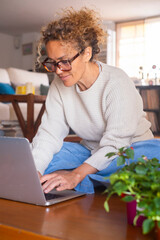 Wall Mural - One woman at home sitting on the floor using laptop in indoor leisure activity. Browsing the net happy. Female people working on computer in house interior. Small business and online