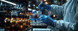 © Hound - A close-up shot of a scientist in protective gear, wear blue medical gloves, applying blue liquid to vials on the production line at his laboratory during science and medical research
