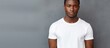 © HN Works - Dark skinned confident and handsome a young American guy in a white t shirt stands against a background allowing for a copy space image