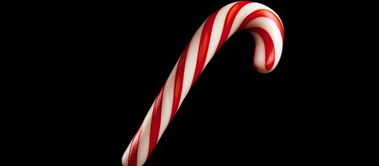 Sticker - Flat lay view of a Christmas candy cane isolated on a black background providing ample copy space in the image