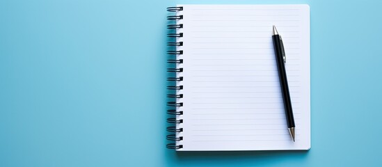 Leinwandbilder - A top view copy space image of a notebook and pen placed on a blue background