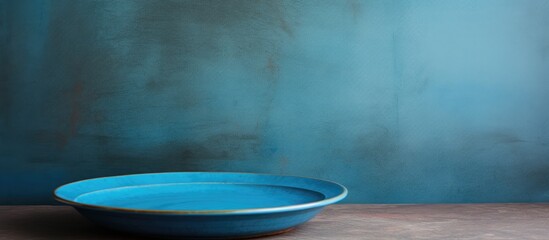 Poster - A perspective view of a blue plate on a cement background with empty space for your design presented as a copy space image