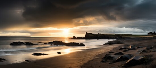 Leinwandbilder - A moody sunrise paints a picturesque scene at Kinghorn beach in Fife with stormy clouds casting a dark hue over the horizon Sunlit waters gently creep onto the beach creating a misty atmosphere The u