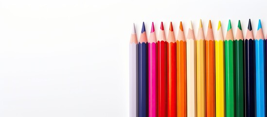 Poster - Color pencils arranged on a blank white drawing paper providing ample copy space for creativity