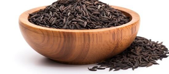 Poster - Copy space image of black cumin seeds presented in a wooden bowl isolated on a white background The pile showcases nigella sativa seeds captured from various angles creating a diverse and visually ap