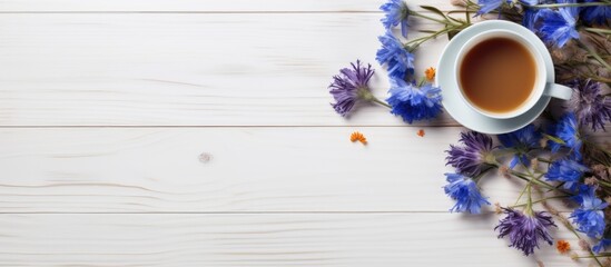 Wall Mural - Flat lay of a cup of tea and cornflowers on a white wooden table with ample copy space for adding text