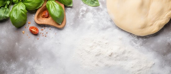 Aufkleber - Front view of a homemade pizza background on a grey kitchen table It features a wooden rolling pin flour and basil leaves with a white wall in the background The image provides ample copy space