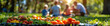 © Carles - Vegetable and fruit foods focused with a family in the background in a natural park, summer concept vacation concept holidays