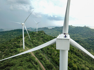 Wind turbine technicians work on the nacelle of a turbine in the wind farm area.