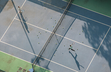 Two tennis players engage in a friendly doubles match on an unoccupied tennis court