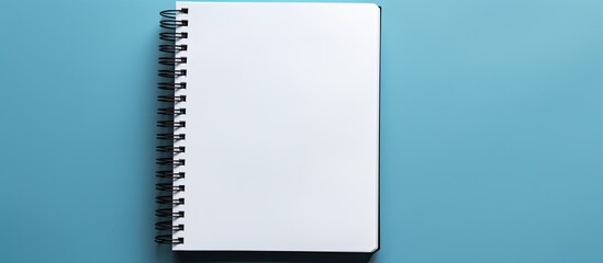 Poster - A black notebook placed by itself against a blue backdrop leaving ample space for additional images or text
