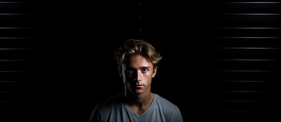 Sticker - A young man standing against black walls with copy space for an image