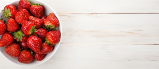 Poster - Top view copy space image of a white wooden background with a heap of fresh strawberries in a bowl