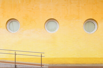 Fototapete - Abstract architecture. Close up of a yellow wall with round windows.