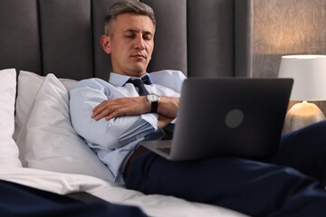 Wall Mural - Businessman with laptop sleeping on bed indoors