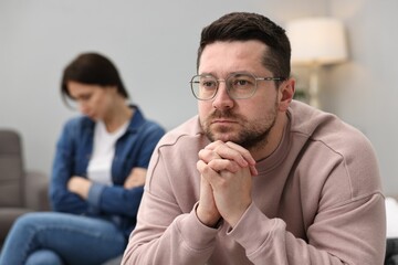 Offended couple ignoring each other after quarrel in bedroom, selective focus. Relationship problems