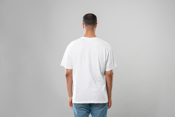 Poster - Man wearing white t-shirt on gray background, back view