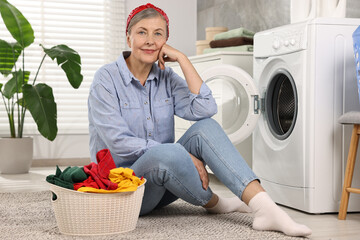 Wall Mural - Smiling housewife with laundry near washing machine at home