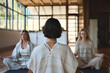 © insta_photos - Rear back view of female yoga coach teaching breathing meditating in studio doing exercises for mind relaxation and mental balance during group class or women retreat training session.