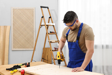 Sticker - Young worker using electric drill at table in workshop