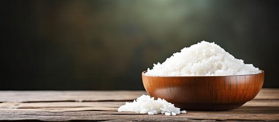 Wall Mural - A copy space image of steamed white rice cooked in a wooden bowl on a rustic table