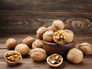Wall Mural - walnuts in a wooden bowl on a brown wooden table