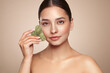 © Oleg Gekman - Beauty young woman doing skin care routine, scrapping, massage facial skin with jade gua sha scrapper, Facial treatment for anti aging and cosmetic cleaning