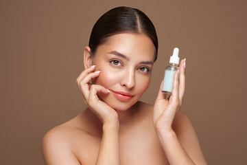 Wall Mural - beautiful elegant woman holding a cosmetic jar of oil serum or hyaluronic acid in her hand. perfect 