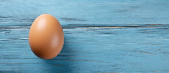 Poster - brown raw chicken egg in shell on old blue wooden background Close up top view. copy space available