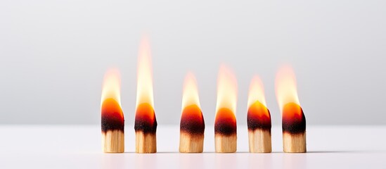 Poster - A copy space image of a row of three matches one of which is lit burning on a white background