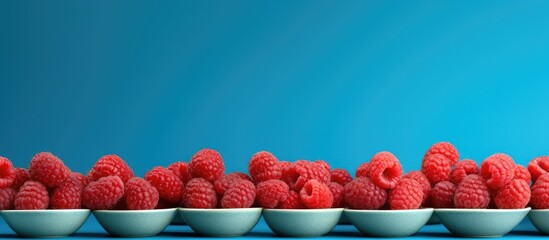 Poster - Bright ripe juicy raspberries on a gray plate on a blue background. copy space available