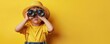 © olegganko - Young Boy With Binoculars and Hat on Yellow Background