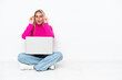 © luismolinero - Young caucasian woman with laptop sitting on the floor with glasses and surprised