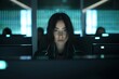 © alisaaa - A young woman is surrounded by monitors & their reflections displaying scrolling text & data