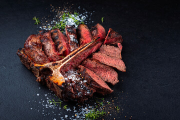 Wall Mural - Barbecue dry aged chianina porterhouse beef steak with crystal salt and thyme served as close-up on black design board