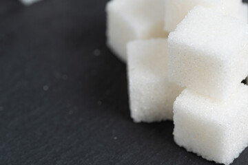 Refined sugar cubes on slate. Food item.