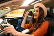 © Home-stock - Overjoyed woman tourist enjoying car ride alone, listening to music, singing songs and dancing while driving auto with backpack nearby on passenger seat