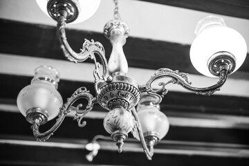 Old vintage chandelier shot close up. Black and white photo of a chandelier hanging from the ceiling