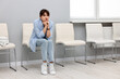 © New Africa - Woman sitting on chair and waiting for appointment indoors