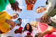 © Xavier Lorenzo - EvotoLow angle view of young group of multicultural women using mobile phones. Millennial females chatting on smart phone at city street. Blue sky.
