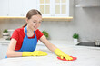 © New Africa - Woman cleaning white marble table with rag in kitchen, space for text