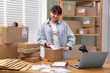 Wall Mural - Parcel packing. Post office worker sticking barcode on box at wooden table indoors