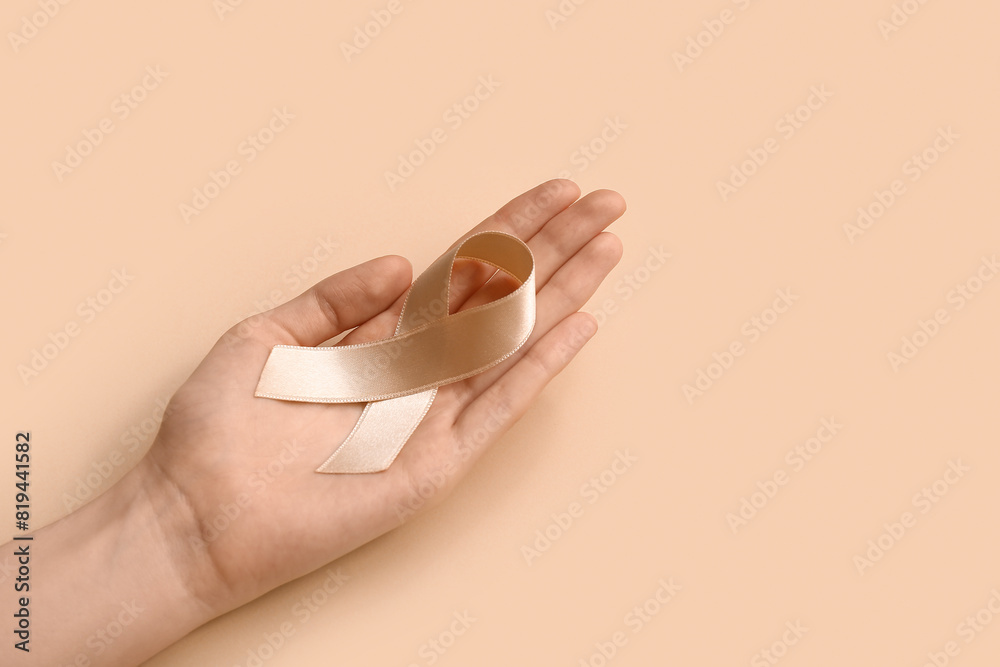 Woman with beige ribbon on color background. Uterine cancer awareness concept