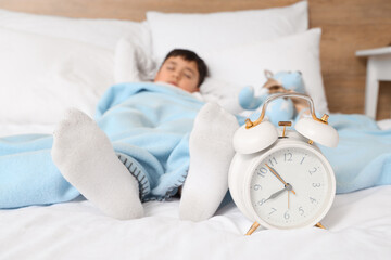 Wall Mural - Cute little boy with teddy bear and alarm clock sleeping in bedroom