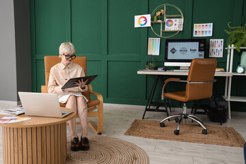 Poster - Young female graphic designer working with tablet on chair in office