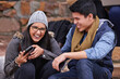 © peopleimages.com - College, phone or funny friends on campus steps for study research, feedback or meme comic. University, smartphone and gen z students with sign up app for streaming, reel or laugh at social media gif