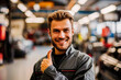 © apratim - Smiling mechanic in a workshop giving a thumbs up. He is confident and professional, standing in an automotive repair environment.