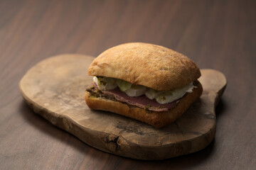 Wall Mural - Roast beef and mozzarella sandwich with ciabatta bun on olive board