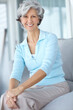 © peopleimages.com - Portrait, smile and senior woman in home on the sofa for relax, comfort or resting alone in living room. Happy pensioner, retirement and person on couch in casual clothes in apartment in Switzerland
