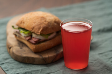 Wall Mural - Roast beef and mozzarella sandwich with ciabatta bun on olive board with red lemonade